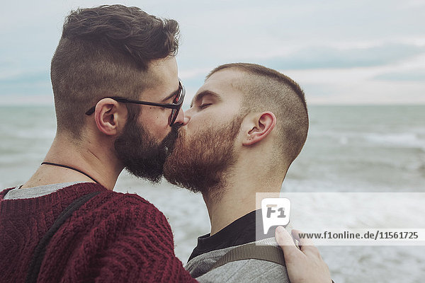 Schwules Paar küsst sich vor dem Meer