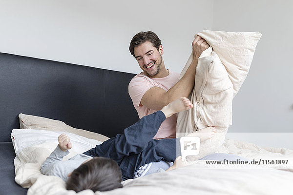 Glücklicher Vater und Sohn beim Spielen im Bett