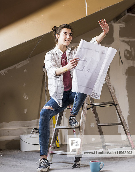 Junge Frau renoviert ihr neues Zuhause  mit Bauplan