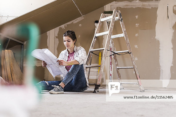 Young woman renovating her new home  holding construction plan