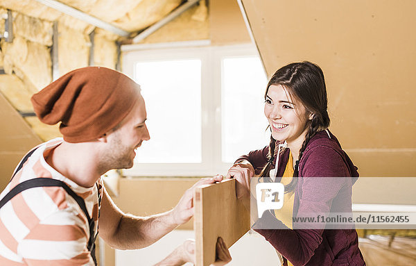 Young man and woman renovating their new home  holding a plank