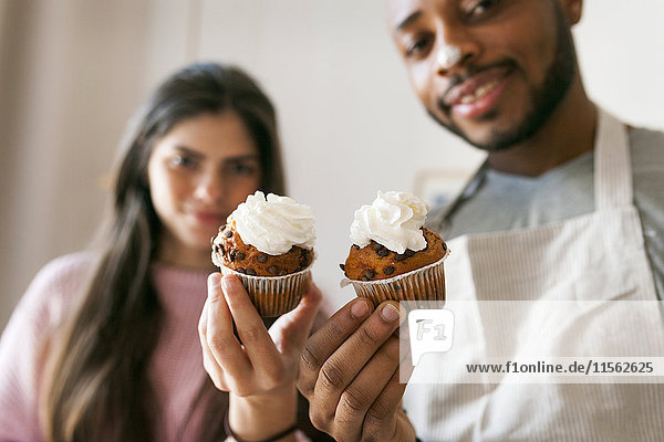 Young couple holding fresh cup cakes