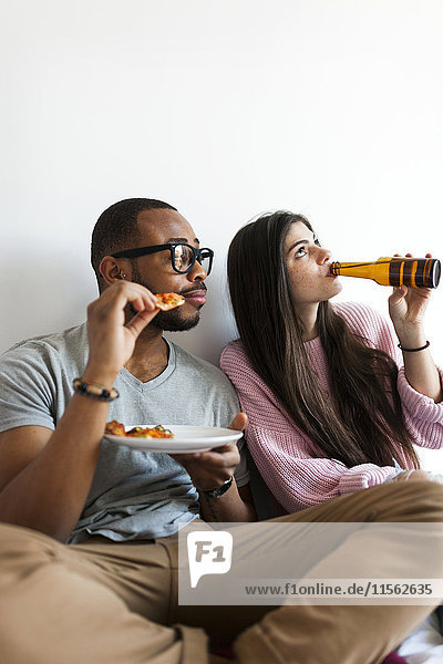 Junges Paar zu Hause beim Pizza essen und Bier trinken
