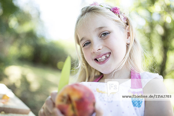 Portrait of smiling girl outdoors holding peach