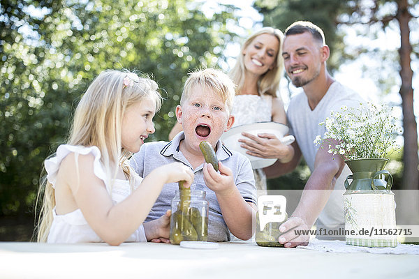 Porträt eines Jungen mit Familie beim Essen von Gurken im Freien