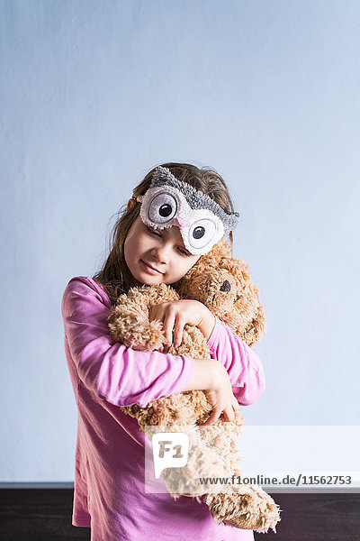Porträt eines Mädchens mit Teddybär und Schlafmaske