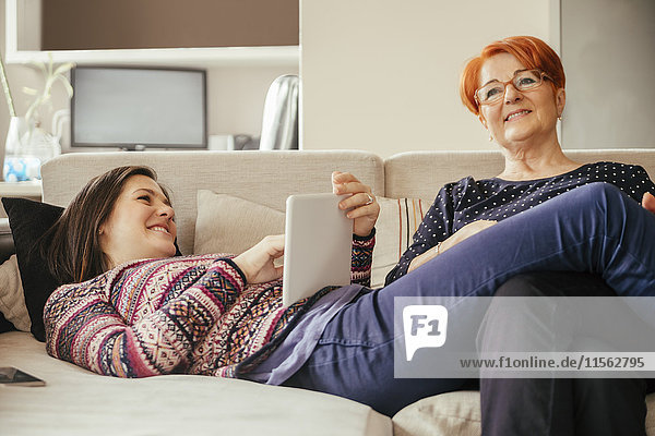 Adult daughter with mother at home using tablet