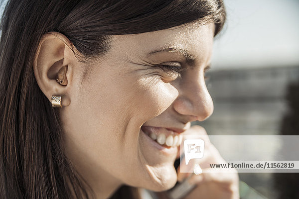 Happy young woman with hearing aid on the phone