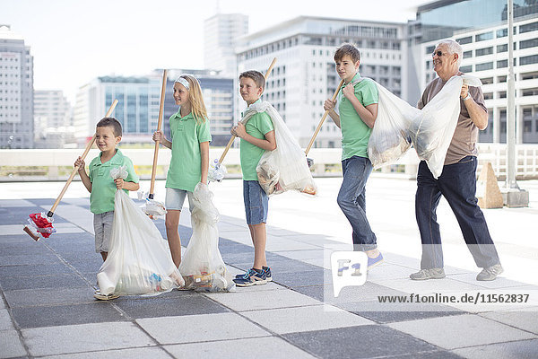 Gruppe von ehrenamtlichen Kindern,  die Müll mit Abfallstäbchen sammeln