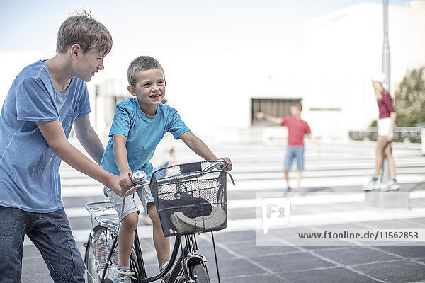 Junge  der dem kleinen Bruder beibringt  wie man ein Fahrrad fährt.