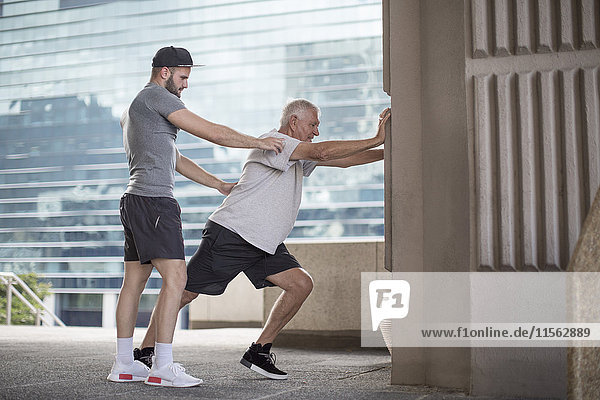 Fitness instructor guiding senior man doing a stretching exercise