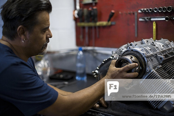 Mechanic working on motorcycle engine in workshop