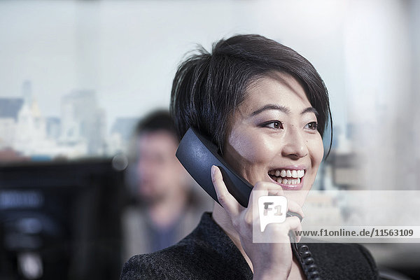Smiling woman in office talking on phone