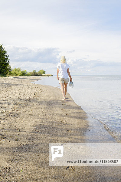 Schweden  Smaland  Visingso  Vattern  Frau beim Spaziergang am Strand am Seeufer