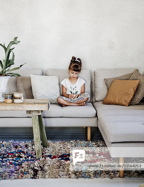 Schweden, Mädchen (4-5) sitzend auf Sofa