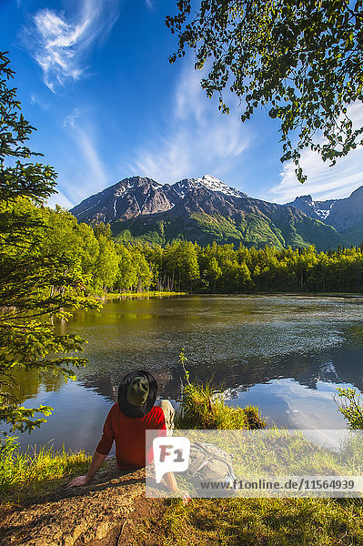 Hiker resting next to Dew Pond in the Chugach State Park near Eagle River  Southcentral Alaska  summer