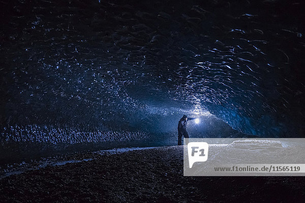 Ein Mann erkundet einen dunklen Tunnel unter dem Eis des Canwell-Gletschers in der Alaska Range.
