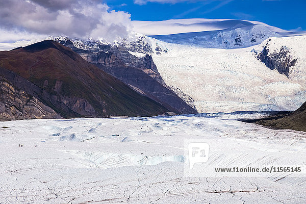 Die Menschen auf dem Root Glacier im Wrangell-St. Elias National Park werden von der umgebenden Landschaft  einschließlich des massiven Stairway Icefall im Hintergrund  in den Schatten gestellt  Süd-Zentral-Alaska  USA
