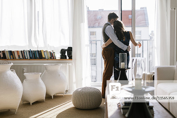 Deutschland Paarumarmung am Fenster im Wohnzimmer
