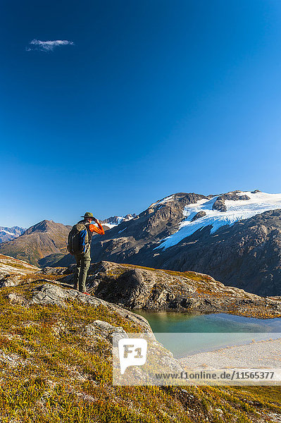 'A man hiking near an unnamed lake near the Harding Icefield Trail in Kenai Fjords National Park on a summer day  South-central Alaska; Alaska  United States of America'