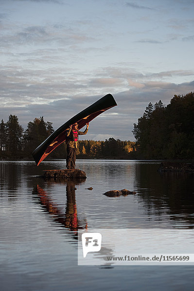 Schweden  Smaland  Mann auf Stein stehend im Seehalterboot