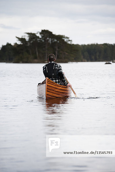 Schweden  Smaland  Reifer Mann im Boot auf dem See mit Wald am Horizont