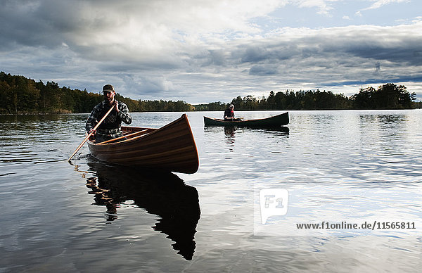 Schweden  Smaland  Reife Männer in Booten auf dem von Wald umgebenen See