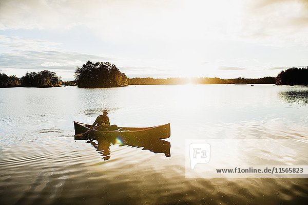 Schweden  Smaland  Erwachsener Mann im Boot auf dem See  umgeben von Wäldern