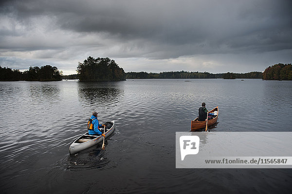 Schweden  Smaland  Reife Männer in Booten auf dem von Wald umgebenen See