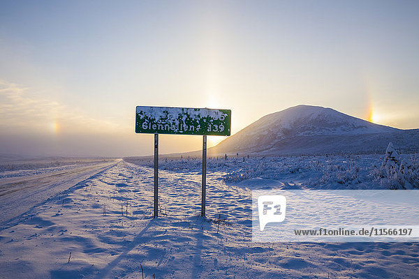 Ein vom Frost teilweise verdecktes Straßenschild entlang des Richardson Highway mit Nebensonnen und dem Donnelly Dome im Hintergrund an einem bitterkalten Wintertag; Alaska  Vereinigte Staaten von Amerika'.