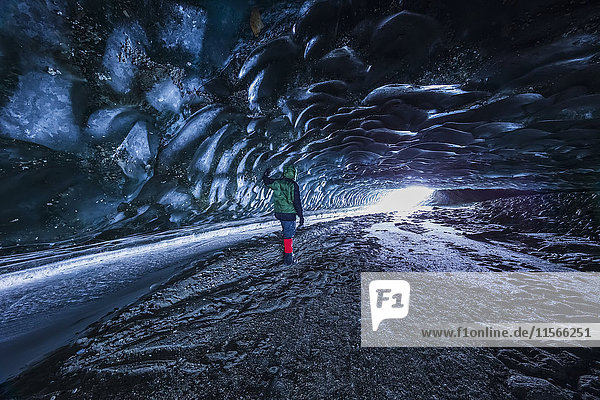 Ein Mann blickt auf den Eingang einer Höhle unter dem Eis des Canwell-Gletschers in der Alaska Range im Winter; Alaska  Vereinigte Staaten von Amerika'.