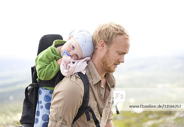 Father hiking with daughter in baby carrier