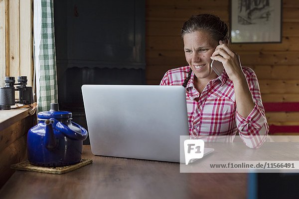 Woman at home on the phone using laptop
