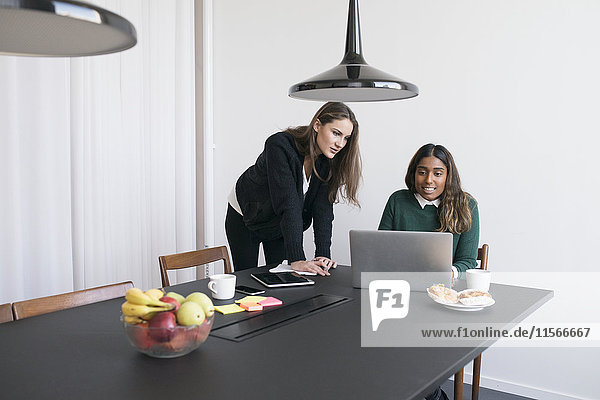 Zwei Frauen benutzen einen Laptop im Büro