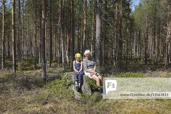 Grandmother with granddaughter sitting in forest