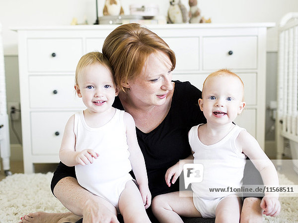 Porträt einer Mutter mit ihren Söhnen (12-17 Monate) im Kinderzimmer