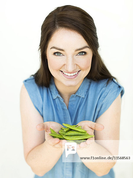 Woman wearing blue top holding sugar snap peas