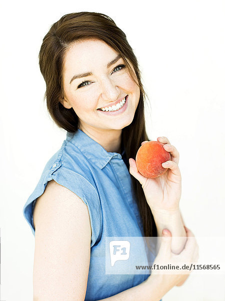 Woman wearing blue top holding peach