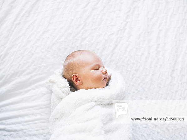 Kleiner Junge (2-5 Monate) schläft in weißer Decke