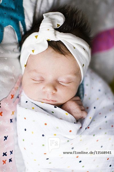Baby-Mädchen (0-1 Monate) in eine Decke gewickelt auf dem Bett schlafend
