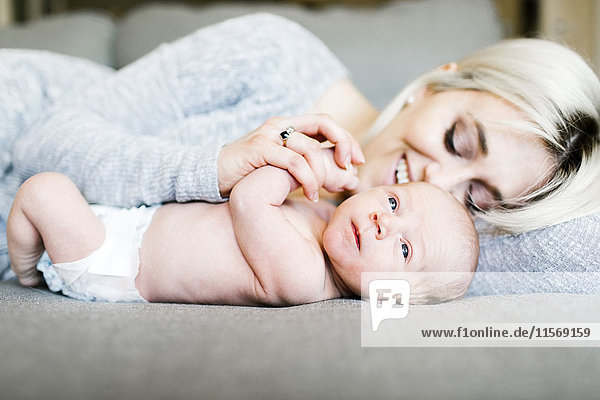 Mutter mit Neugeborenem (0-1 Monate) auf dem Sofa liegend