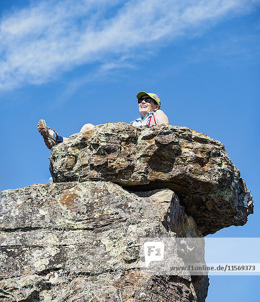 Niedriger Blickwinkel auf eine auf einem Felsen sitzende Frau
