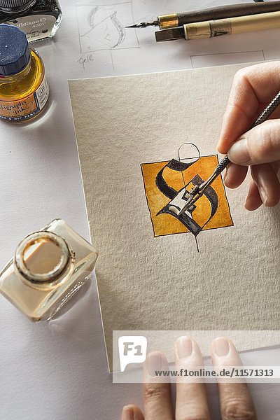 Kalligraphie  Atelier  Hand malt Vergoldung mit Zeichenfeder  Buchstaben S auf Torchonpapier  Tintenfaß und Füllfederhalter im Hintergrund  Seebruck  Oberbayern  Deutschland  Europa