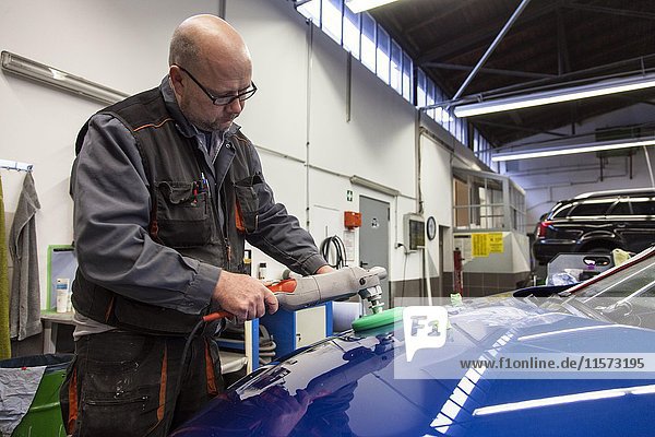 Coachbuilder master with the polishing machine on the car  Düsseldorf  North Rhine-Westphalia  Germany  Europe
