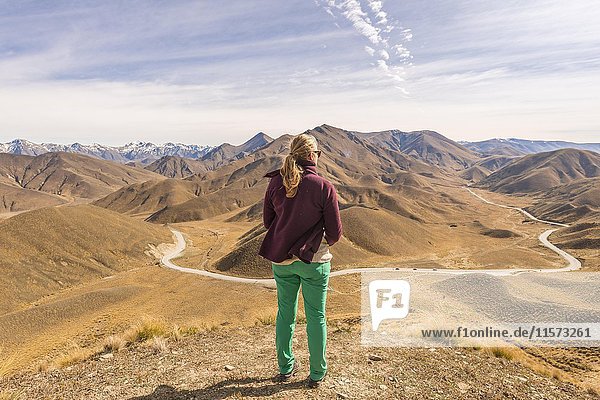 Frau blickt über karge Berge  Lindis Pass  Südliche Alpen  Otago  Südland  Neuseeland  Ozeanien
