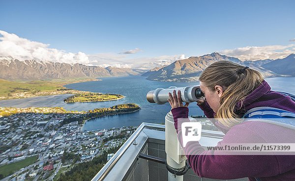 Frau schaut durch ein Teleskop  Blick auf den Lake Wakatipu und Queenstown von der Skyline Gondola  Gondelbahn  Ben Lomond Scenic Reserve  Otago  Southland  Neuseeland  Ozeanien