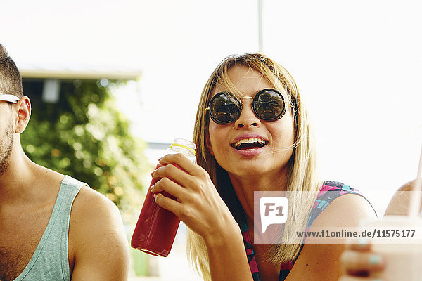Male and female friends relaxing with drinks in park