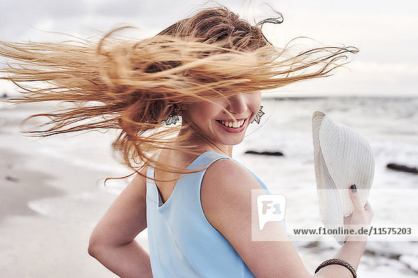 Frau schwingt Haare am Strand herum