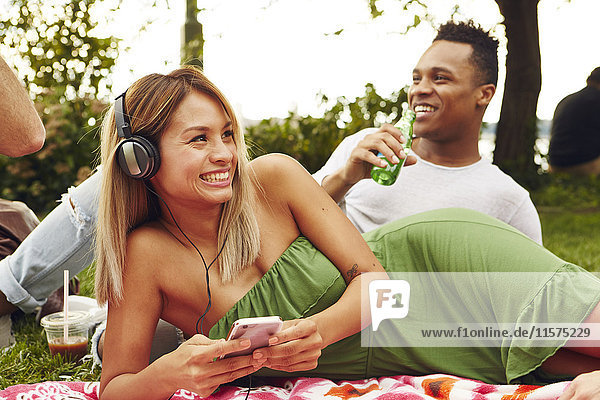 Frau wählt Smartphone-Musik beim Picknick im Park