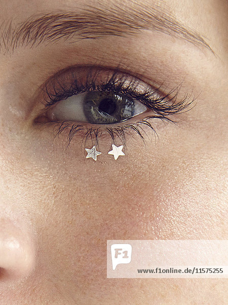 Close up of glitter stars under young woman's eye